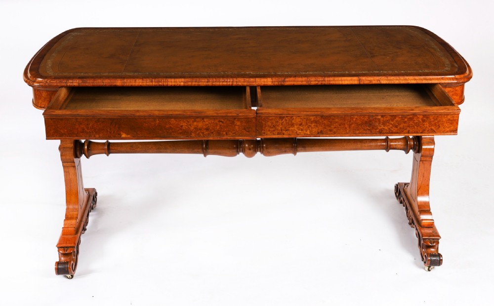 A 19th-century Victorian pollard oak writing table featuring a brown leather inset top, carved trestle end supports, a turned central stretcher, and scroll feet on brass castors. View XI
