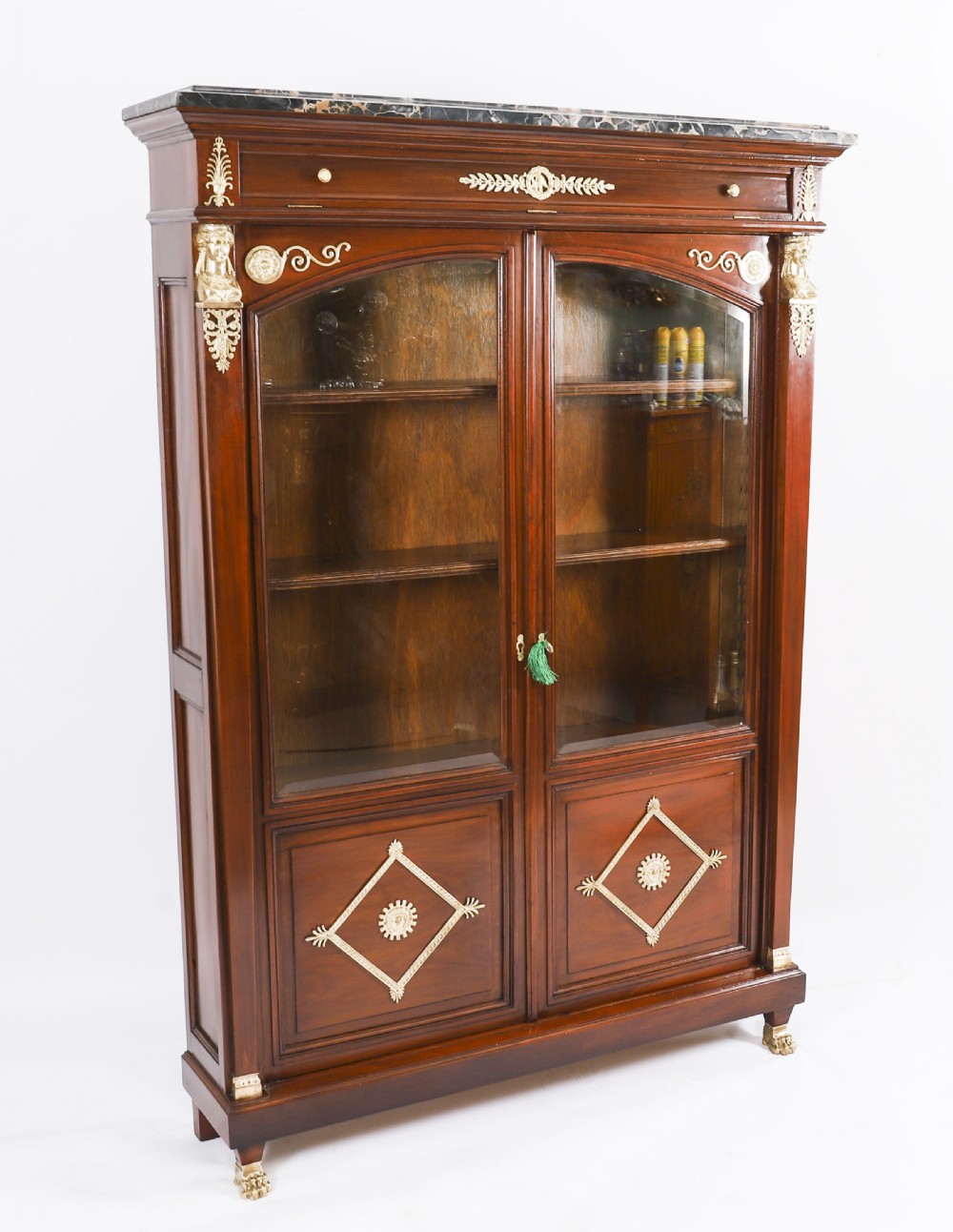 A nineteenth-century French Empire Revival mahogany bookcase featuring twin glazed doors, gilt bronze mounts, a marble top, and metal paw feet. View II