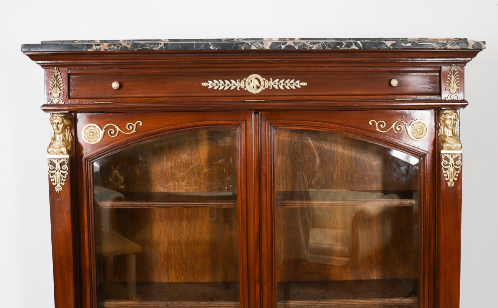 A nineteenth-century French Empire Revival mahogany bookcase featuring twin glazed doors, gilt bronze mounts, a marble top, and metal paw feet. View IV