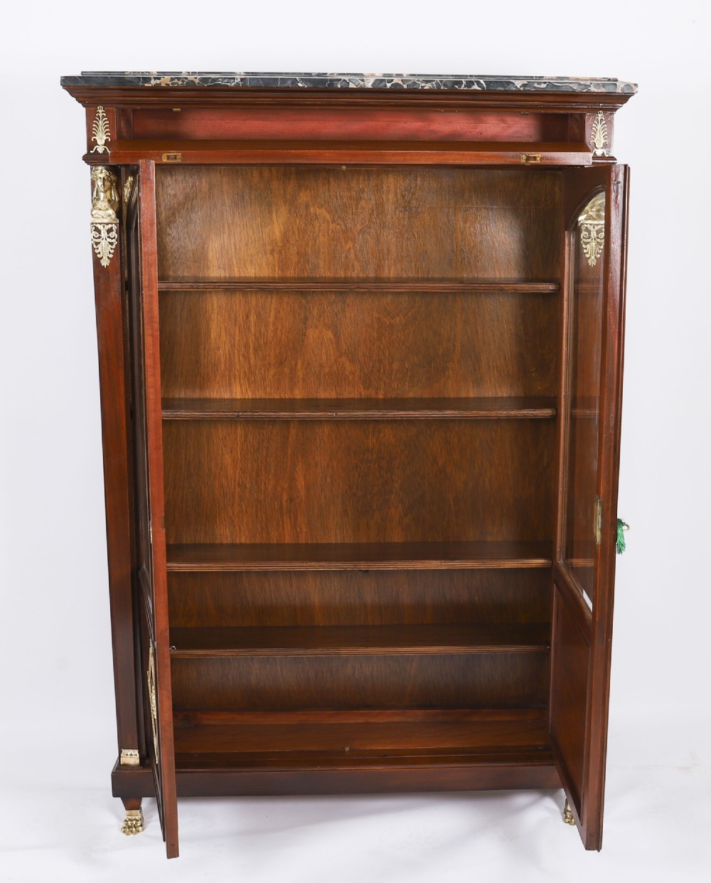 A nineteenth-century French Empire Revival mahogany bookcase featuring twin glazed doors, gilt bronze mounts, a marble top, and metal paw feet. View XII