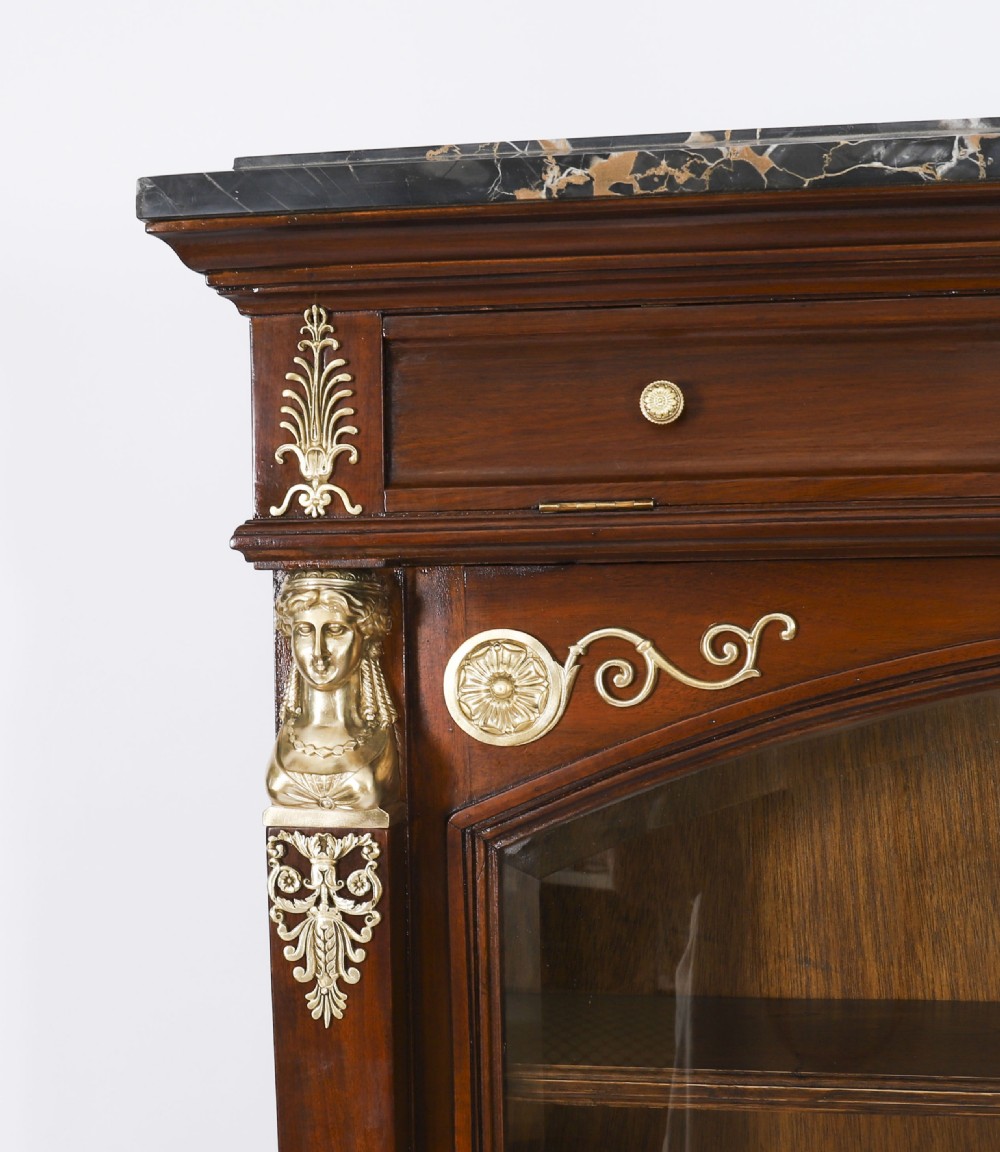 A nineteenth-century French Empire Revival mahogany bookcase featuring twin glazed doors, gilt bronze mounts, a marble top, and metal paw feet. View XIII