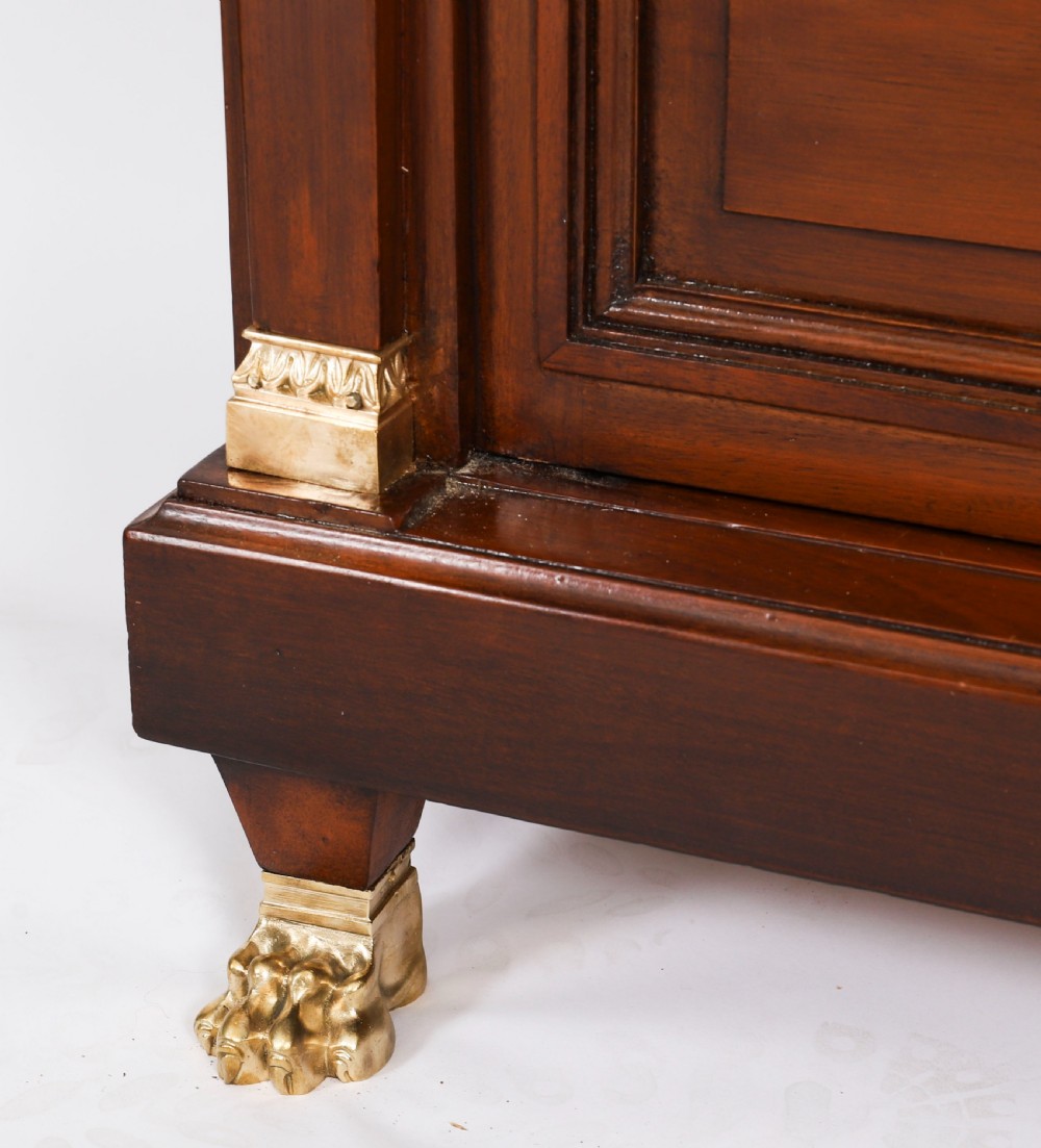 A nineteenth-century French Empire Revival mahogany bookcase featuring twin glazed doors, gilt bronze mounts, a marble top, and metal paw feet. View XVII