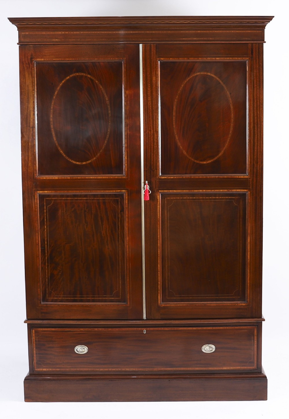 A late 19th-century George III revival flame mahogany double wardrobe featuring oval panel inlays, twin doors, a single bottom drawer, and a moulded cornice.