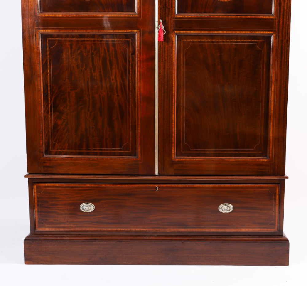 A late 19th-century George III revival flame mahogany double wardrobe featuring oval panel inlays, twin doors, a single bottom drawer, and a moulded cornice. View IV