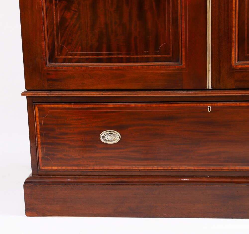 A late 19th-century George III revival flame mahogany double wardrobe featuring oval panel inlays, twin doors, a single bottom drawer, and a moulded cornice. View V