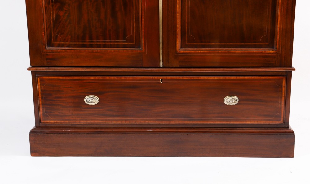 A late 19th-century George III revival flame mahogany double wardrobe featuring oval panel inlays, twin doors, a single bottom drawer, and a moulded cornice. View VI