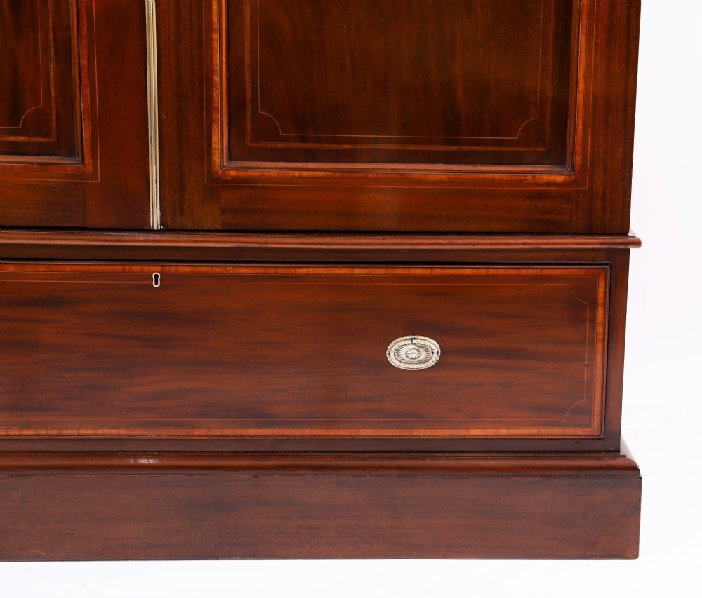 A late 19th-century George III revival flame mahogany double wardrobe featuring oval panel inlays, twin doors, a single bottom drawer, and a moulded cornice. View VII