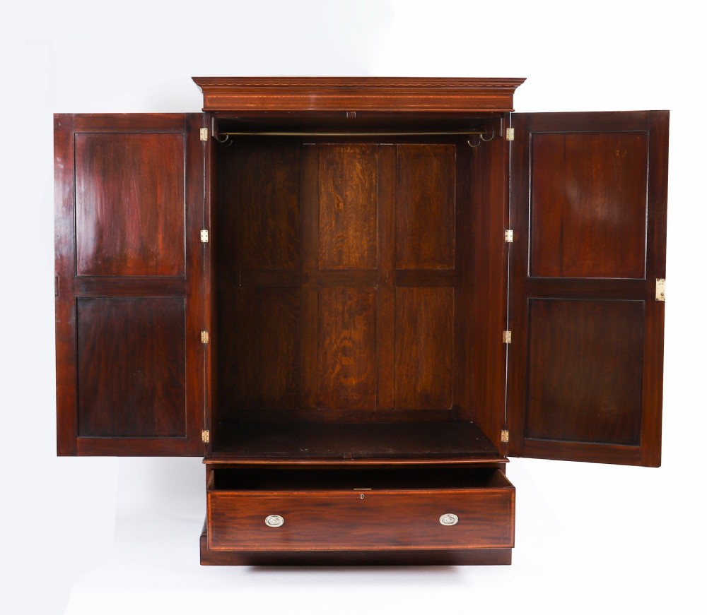 A late 19th-century George III revival flame mahogany double wardrobe featuring oval panel inlays, twin doors, a single bottom drawer, and a moulded cornice. View XII