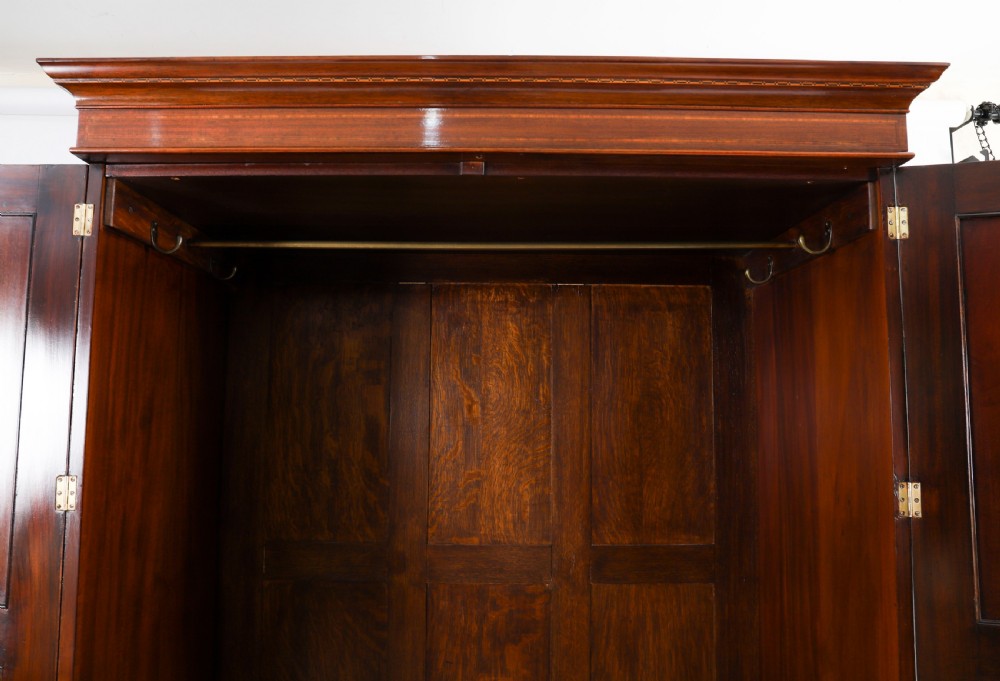 A late 19th-century George III revival flame mahogany double wardrobe featuring oval panel inlays, twin doors, a single bottom drawer, and a moulded cornice. View XIII