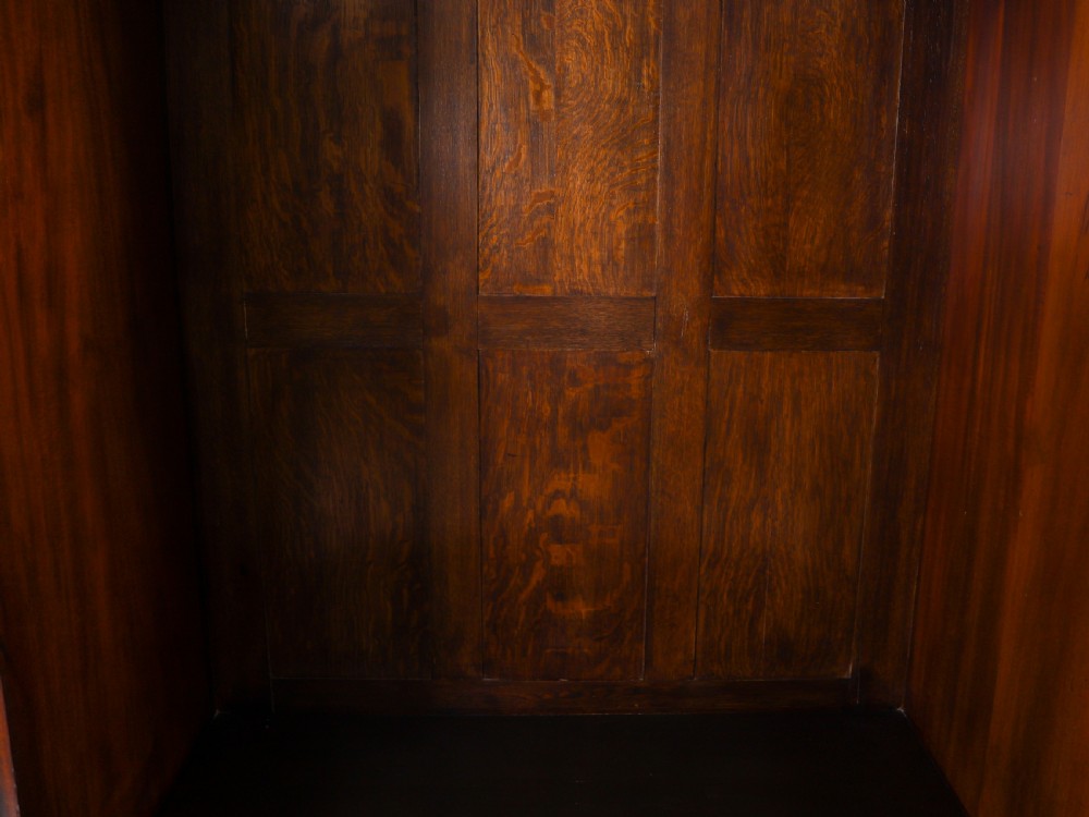 A late 19th-century George III revival flame mahogany double wardrobe featuring oval panel inlays, twin doors, a single bottom drawer, and a moulded cornice. View XIV