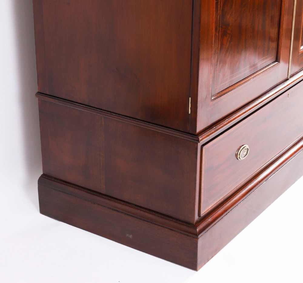 A late 19th-century George III revival flame mahogany double wardrobe featuring oval panel inlays, twin doors, a single bottom drawer, and a moulded cornice. View XVIII