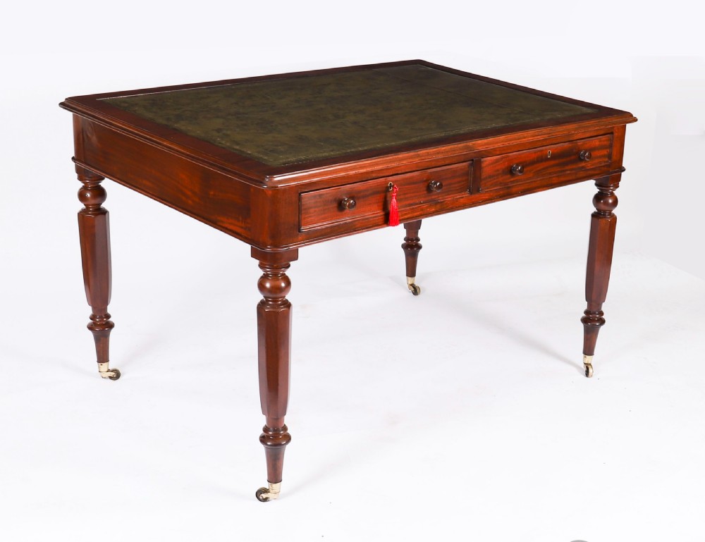 A nineteenth-century Victorian mahogany partners writing desk featuring a green leather inset top, frieze drawers with turned wood knob handles, and tapered legs on brass castors.
