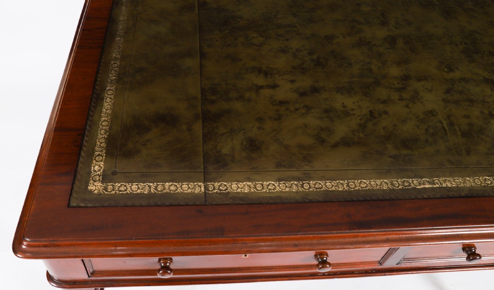 A nineteenth-century Victorian mahogany partners writing desk featuring a green leather inset top, frieze drawers with turned wood knob handles, and tapered legs on brass castors. View III