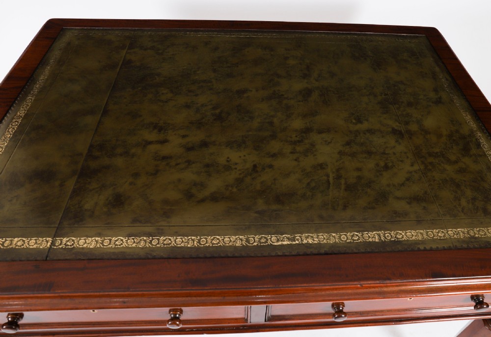 A nineteenth-century Victorian mahogany partners writing desk featuring a green leather inset top, frieze drawers with turned wood knob handles, and tapered legs on brass castors. View IV