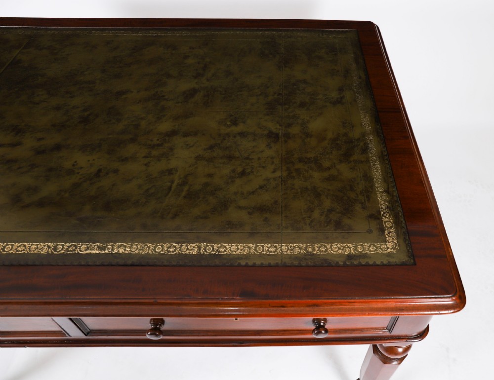 A nineteenth-century Victorian mahogany partners writing desk featuring a green leather inset top, frieze drawers with turned wood knob handles, and tapered legs on brass castors. View V
