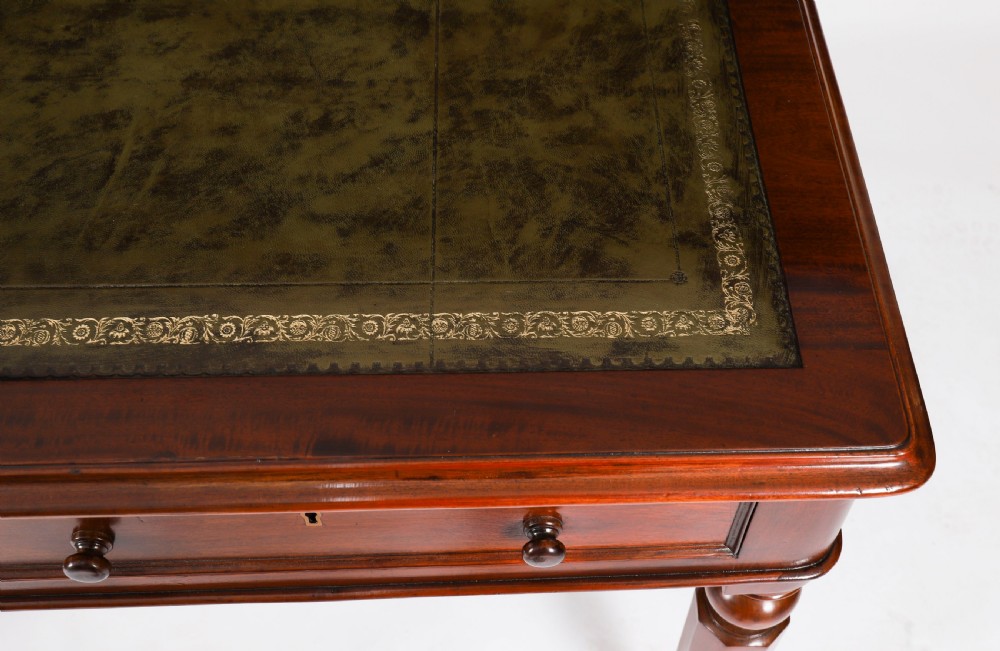 A nineteenth-century Victorian mahogany partners writing desk featuring a green leather inset top, frieze drawers with turned wood knob handles, and tapered legs on brass castors. View VI
