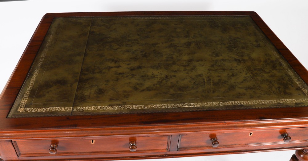 A nineteenth-century Victorian mahogany partners writing desk featuring a green leather inset top, frieze drawers with turned wood knob handles, and tapered legs on brass castors. View VII