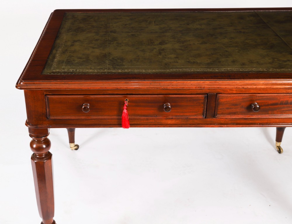 A nineteenth-century Victorian mahogany partners writing desk featuring a green leather inset top, frieze drawers with turned wood knob handles, and tapered legs on brass castors. View VIII
