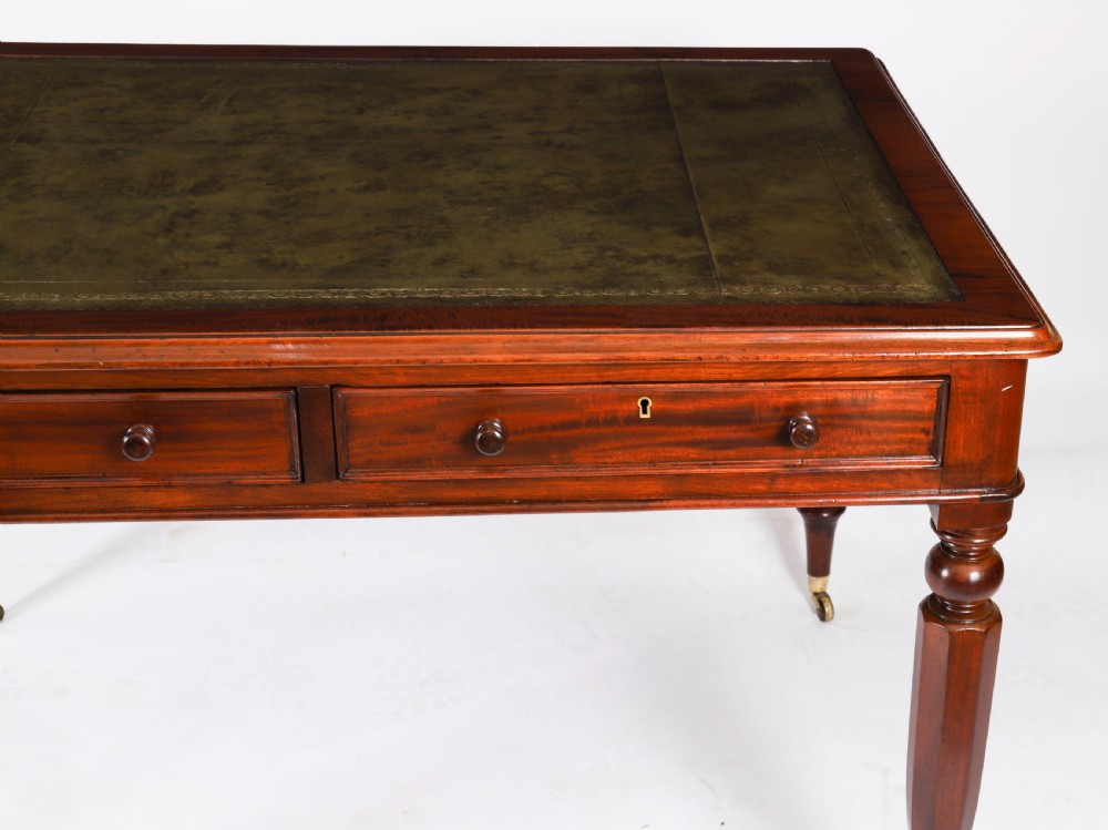 A nineteenth-century Victorian mahogany partners writing desk featuring a green leather inset top, frieze drawers with turned wood knob handles, and tapered legs on brass castors. View IX