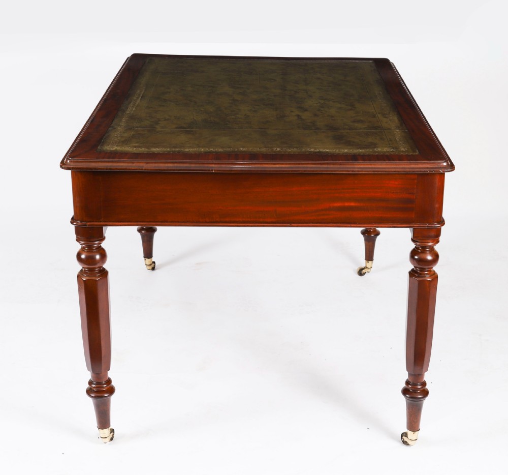 A nineteenth-century Victorian mahogany partners writing desk featuring a green leather inset top, frieze drawers with turned wood knob handles, and tapered legs on brass castors. View X