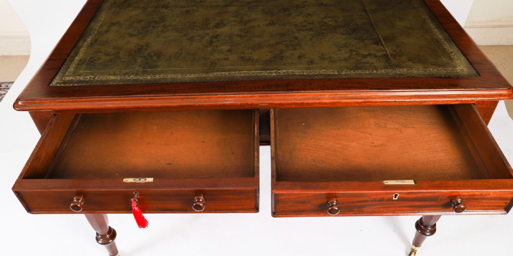 A nineteenth-century Victorian mahogany partners writing desk featuring a green leather inset top, frieze drawers with turned wood knob handles, and tapered legs on brass castors. View XII