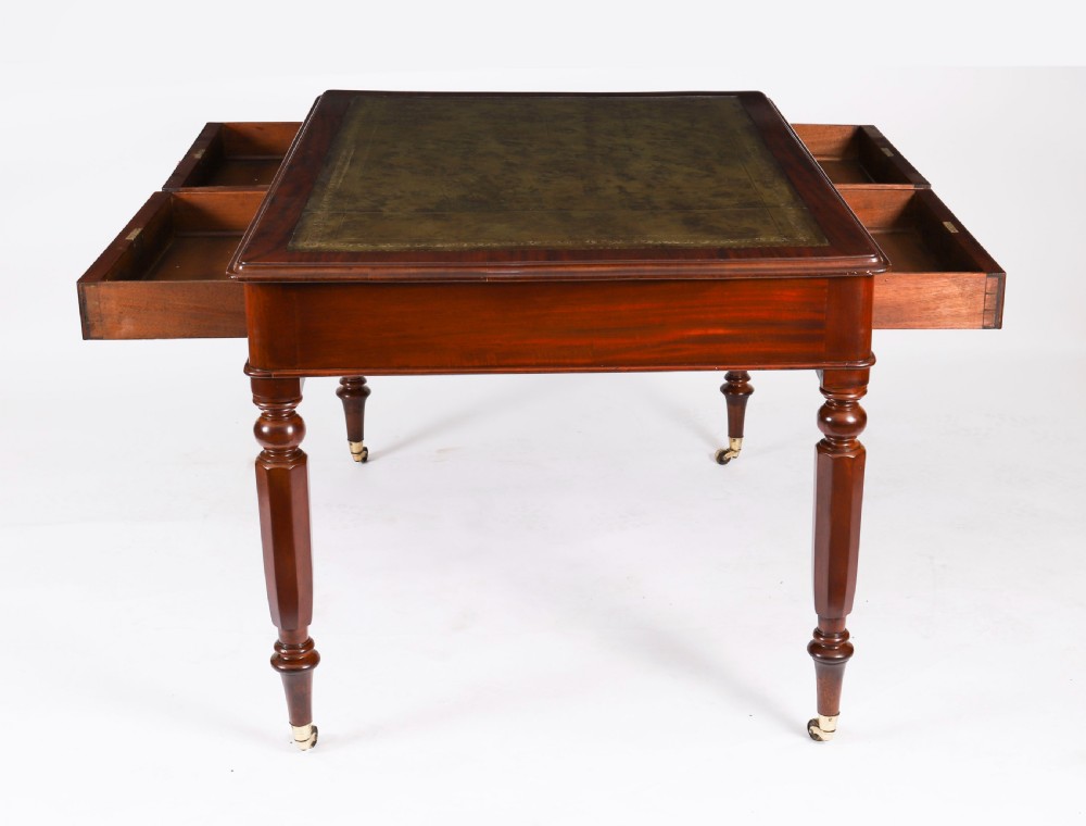 A nineteenth-century Victorian mahogany partners writing desk featuring a green leather inset top, frieze drawers with turned wood knob handles, and tapered legs on brass castors. View XIV