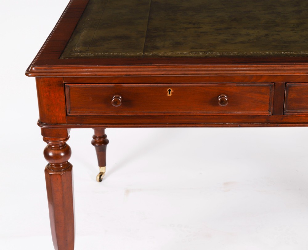 A nineteenth-century Victorian mahogany partners writing desk featuring a green leather inset top, frieze drawers with turned wood knob handles, and tapered legs on brass castors. View XV