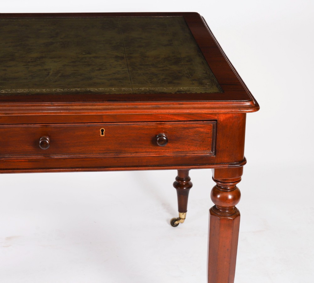 A nineteenth-century Victorian mahogany partners writing desk featuring a green leather inset top, frieze drawers with turned wood knob handles, and tapered legs on brass castors. View XVI