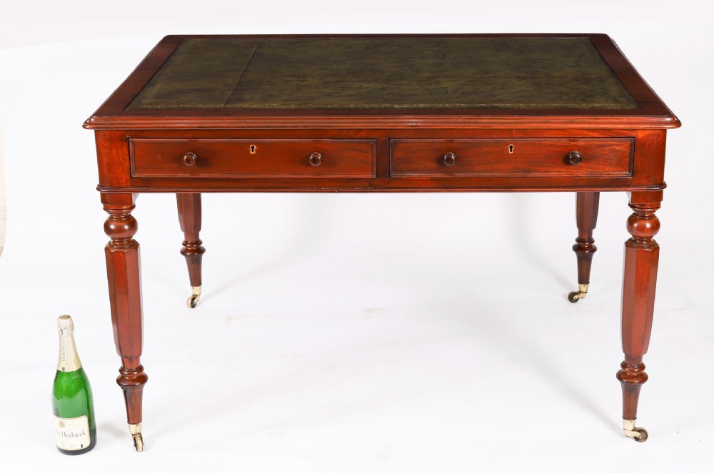 A nineteenth-century Victorian mahogany partners writing desk featuring a green leather inset top, frieze drawers with turned wood knob handles, and tapered legs on brass castors. View XVII