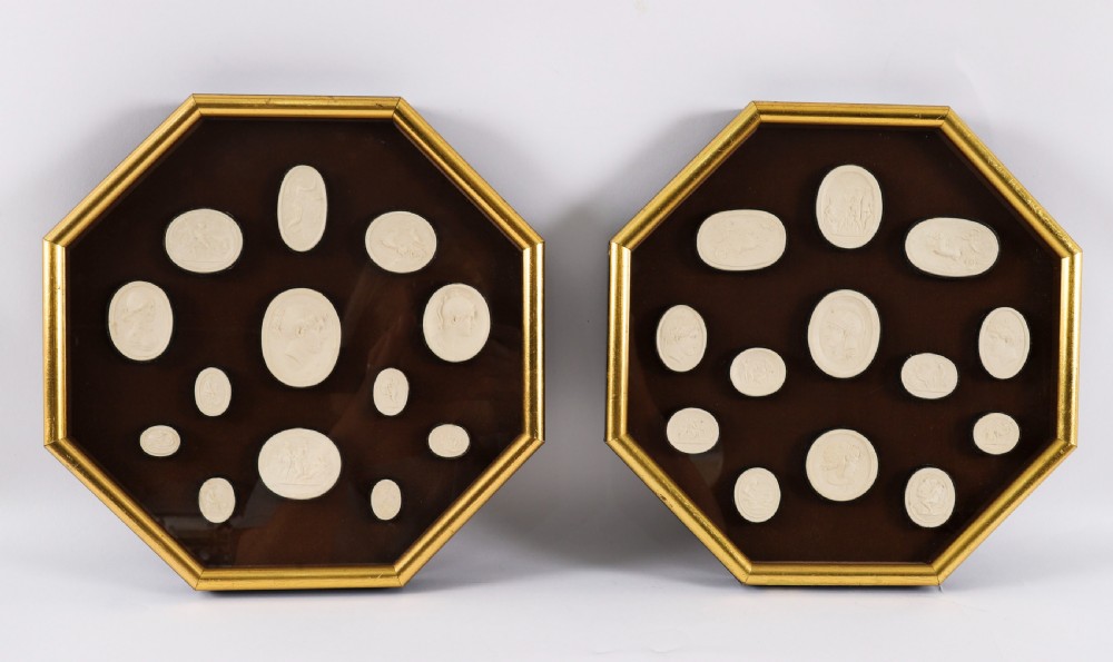 A pair of octagonal giltwood framed wall displays featuring multiple cream plaster intaglio impressions mounted against a dark brown background.