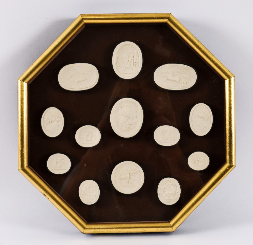 A pair of octagonal giltwood framed wall displays featuring multiple cream plaster intaglio impressions mounted against a dark brown background. View VII