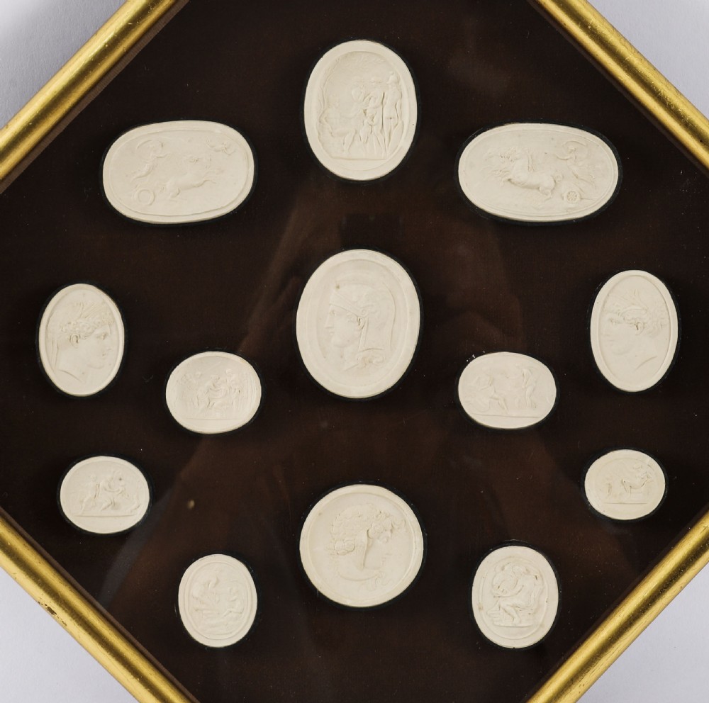 A pair of octagonal giltwood framed wall displays featuring multiple cream plaster intaglio impressions mounted against a dark brown background. View VIII