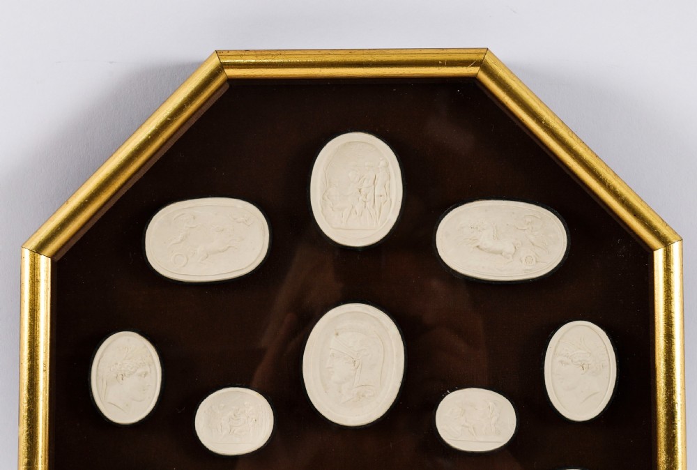 A pair of octagonal giltwood framed wall displays featuring multiple cream plaster intaglio impressions mounted against a dark brown background. View XI