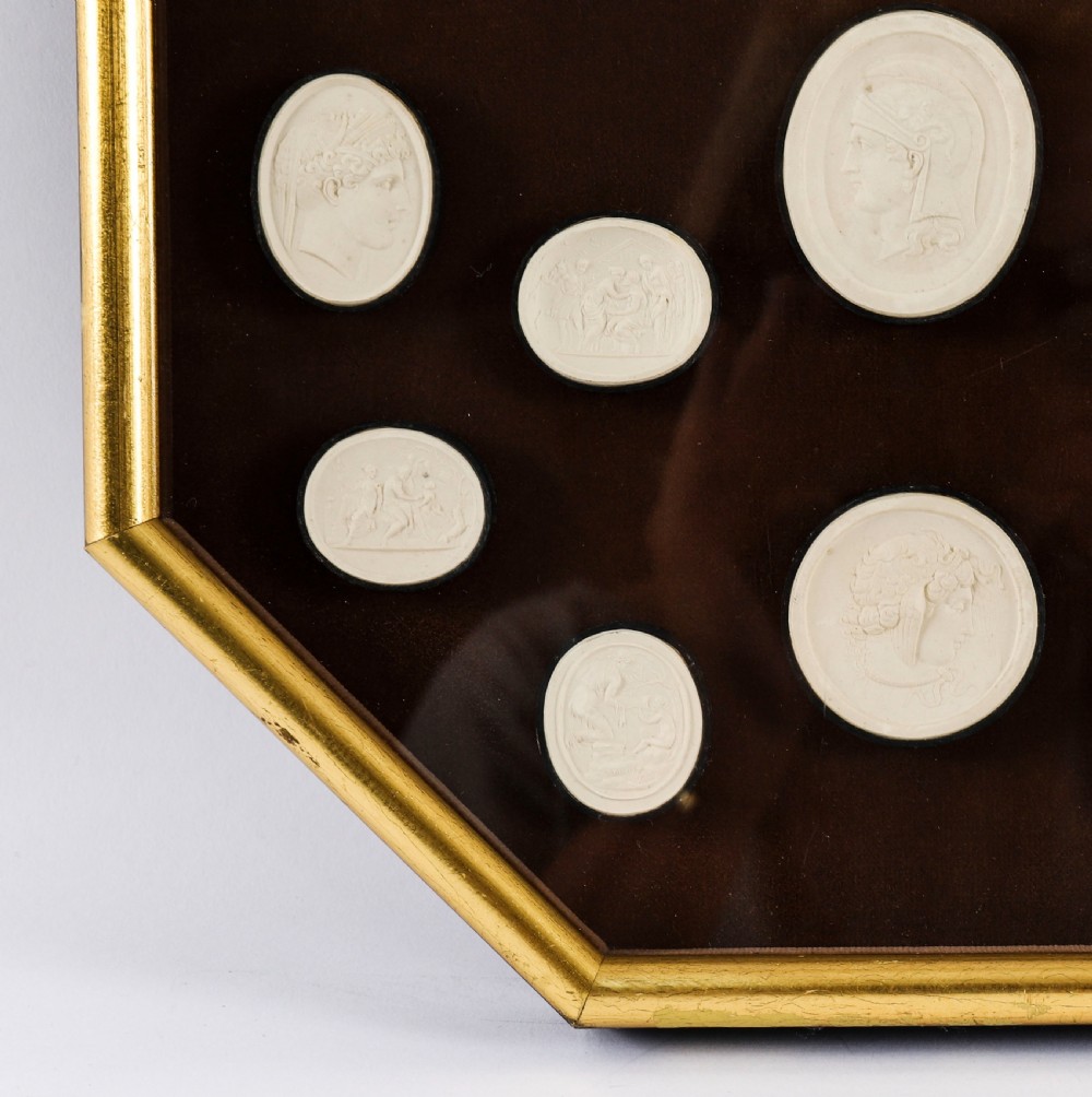 A pair of octagonal giltwood framed wall displays featuring multiple cream plaster intaglio impressions mounted against a dark brown background. View XIII
