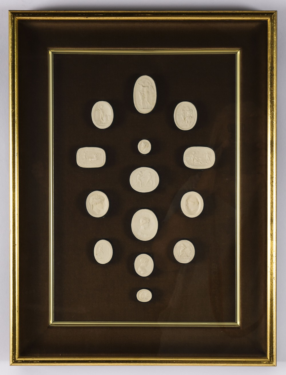 A pair of dark velvet-lined gilt frames containing arrangements of white plaster classical intaglio cameos. View II