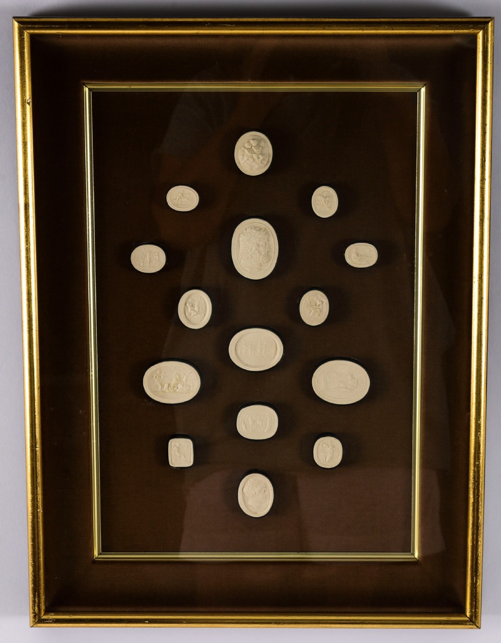A pair of dark velvet-lined gilt frames containing arrangements of white plaster classical intaglio cameos. View X