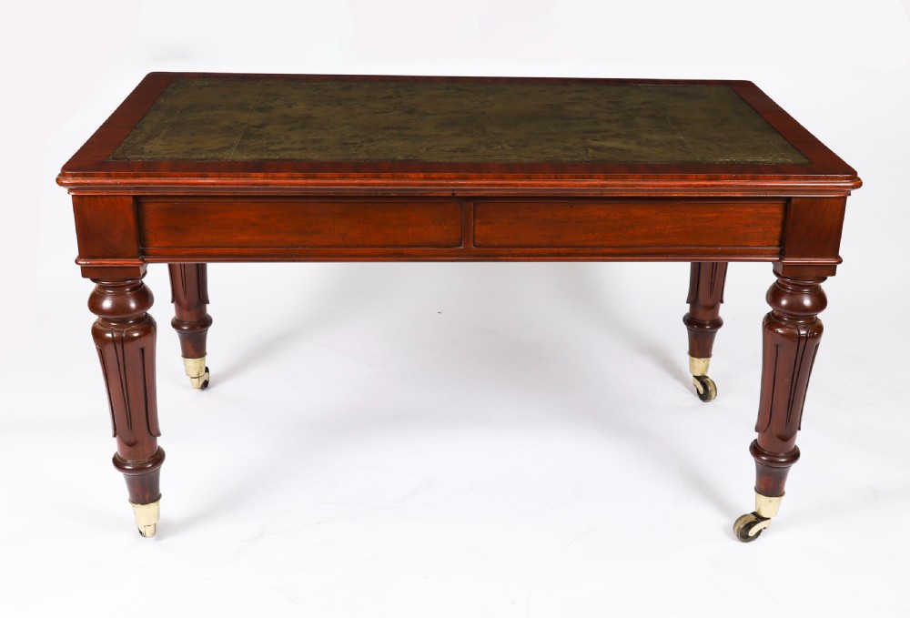 A William IV mahogany writing desk featuring an inset green leather surface, two frieze drawers with knob handles, turned fluted legs, and brass castors. View VII