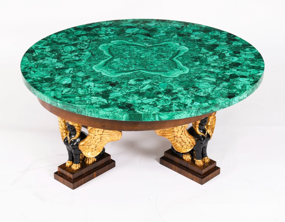 A round coffee table featuring a green malachite stone veneer top supported by three carved ebonised and giltwood winged sphinx legs on dark plinth bases. View III