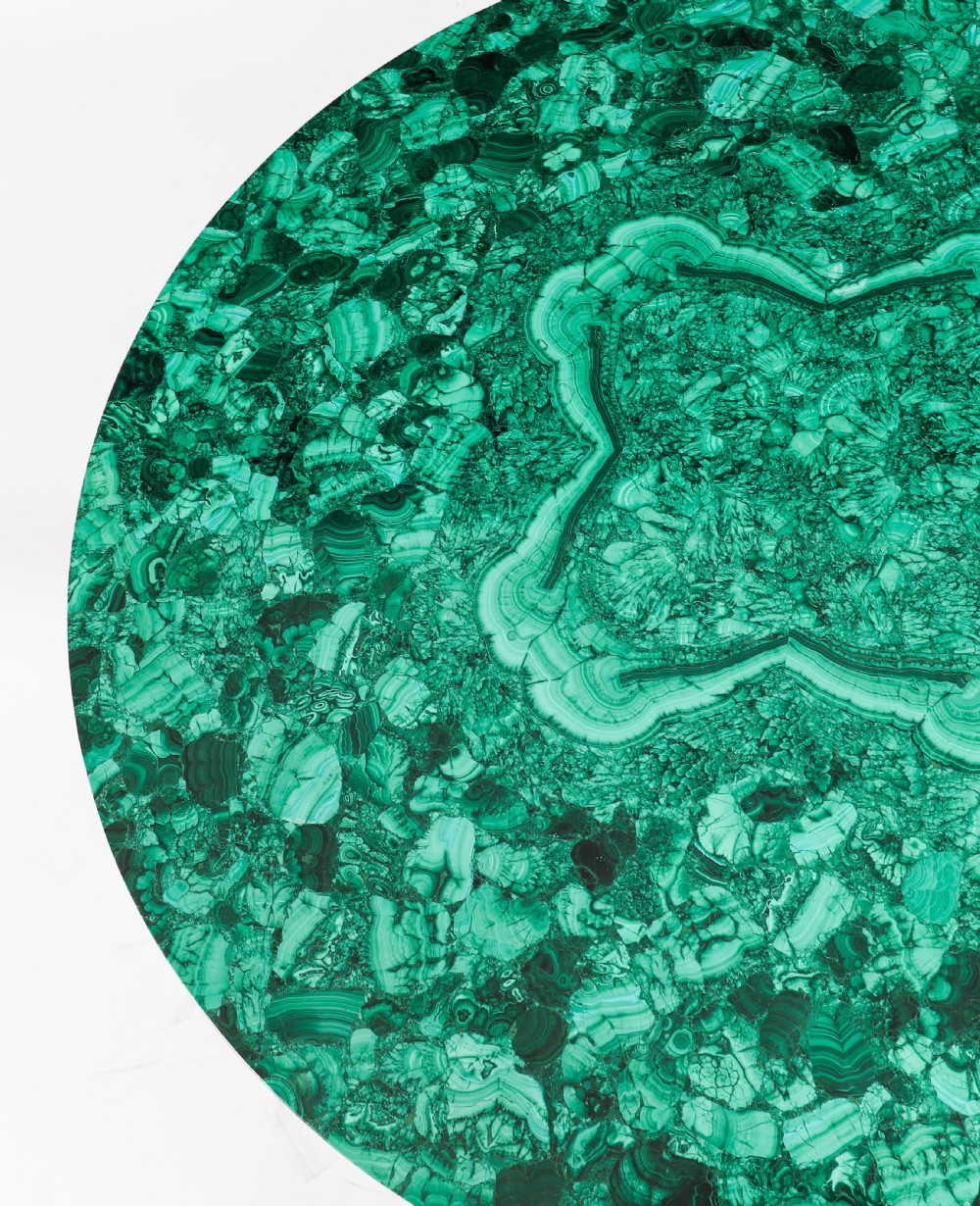 A round coffee table featuring a green malachite stone veneer top supported by three carved ebonised and giltwood winged sphinx legs on dark plinth bases. View X