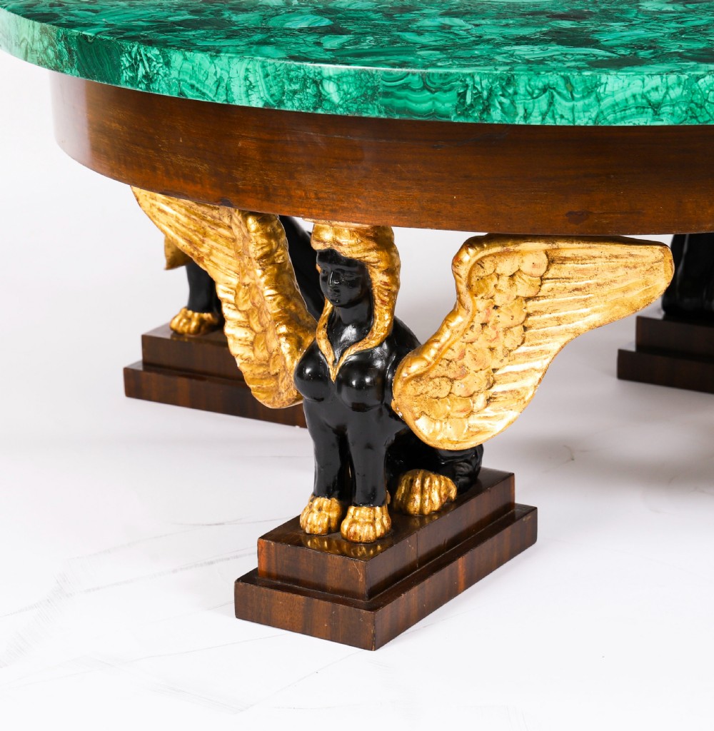 A round coffee table featuring a green malachite stone veneer top supported by three carved ebonised and giltwood winged sphinx legs on dark plinth bases. View XVI