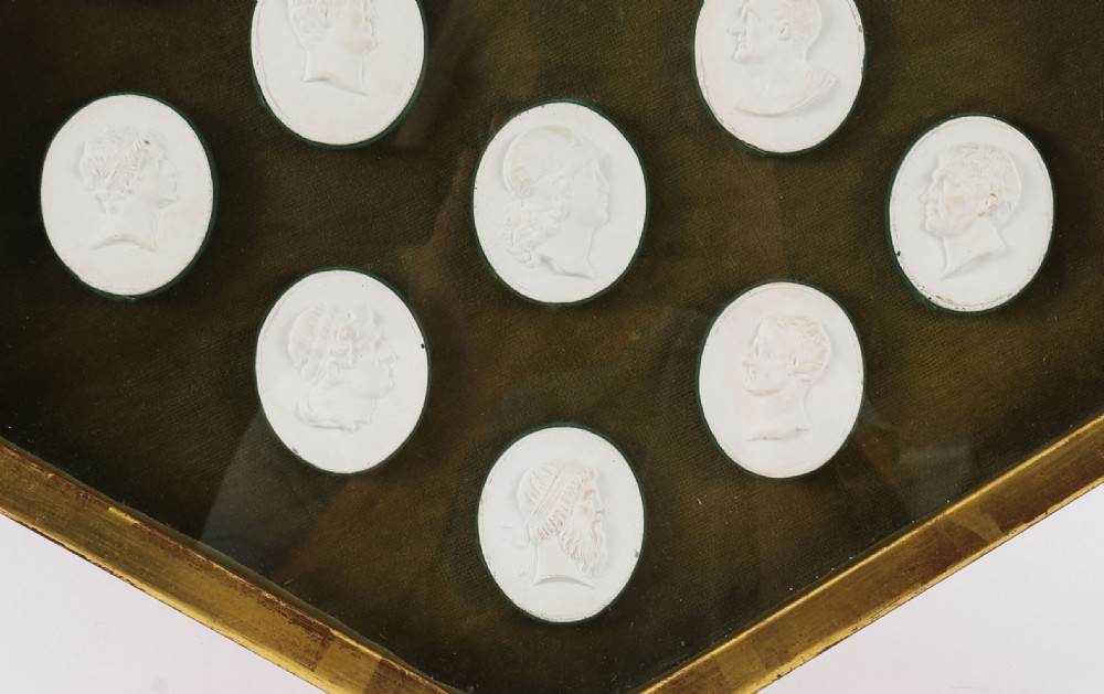 A hexagonal giltwood frame housing thirteen classical white plaster profile intaglios mounted against a dark green background. View III