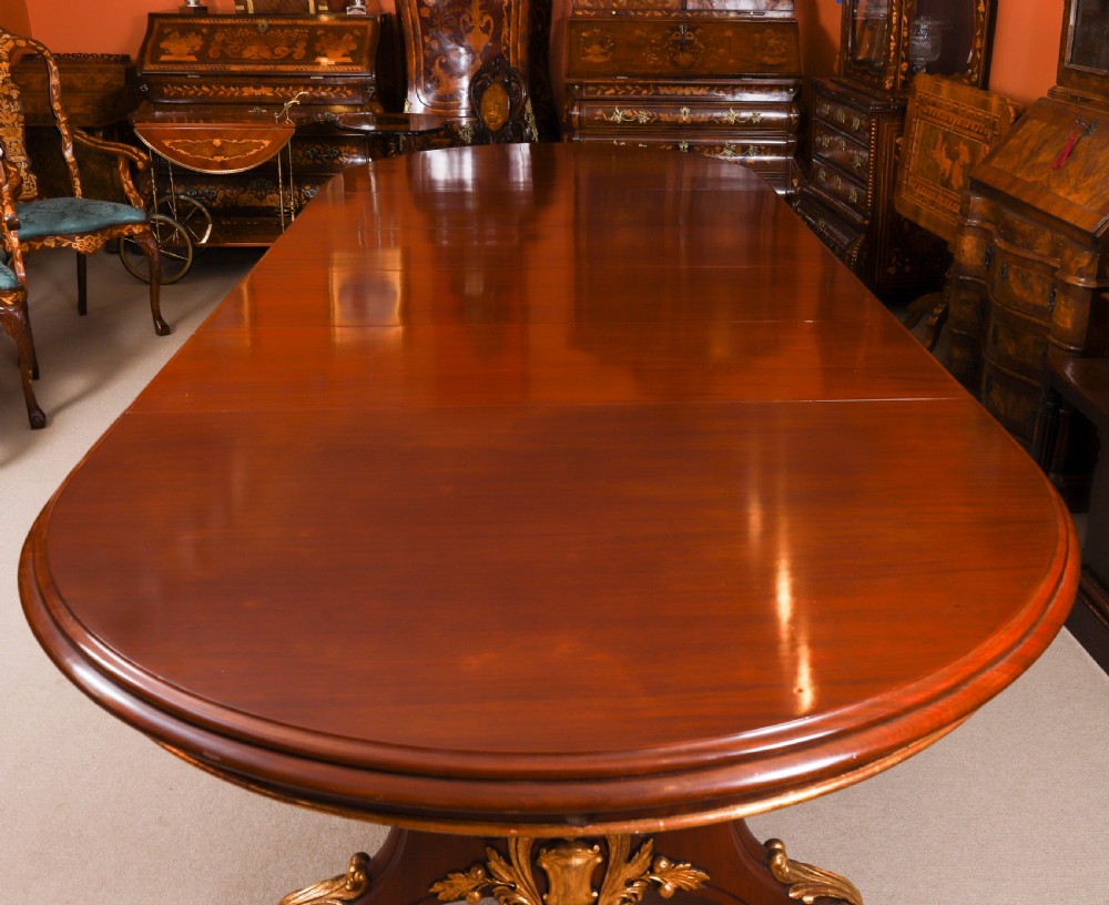 A large, polished mahogany extending dining table supported by two carved twin pedestals with parcel-gilt detailing. View VI