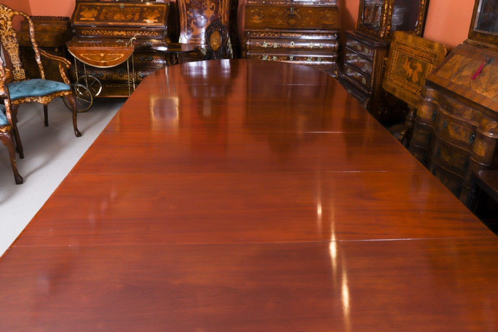 A large, polished mahogany extending dining table supported by two carved twin pedestals with parcel-gilt detailing. View VIII