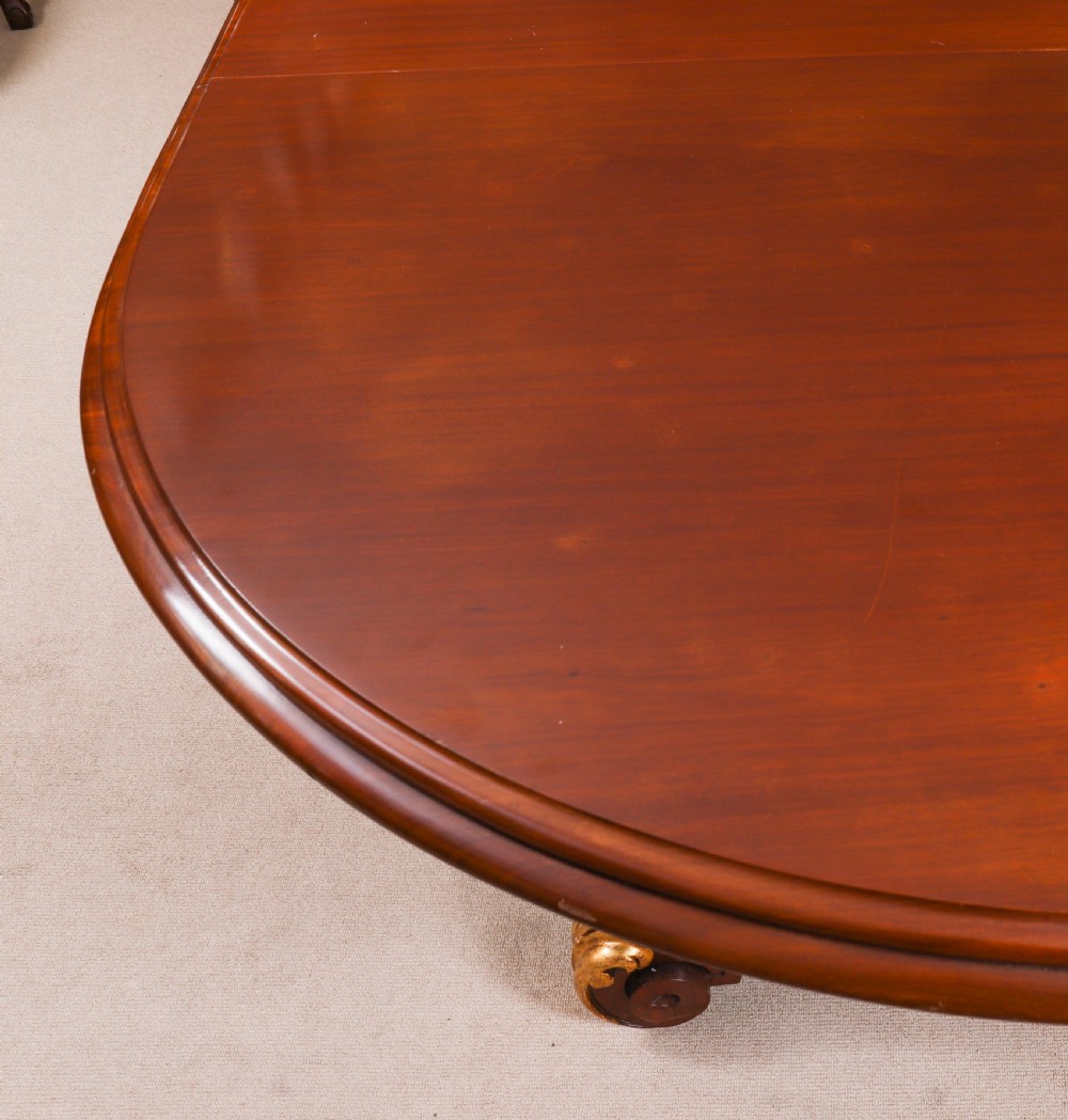 A large, polished mahogany extending dining table supported by two carved twin pedestals with parcel-gilt detailing. View X