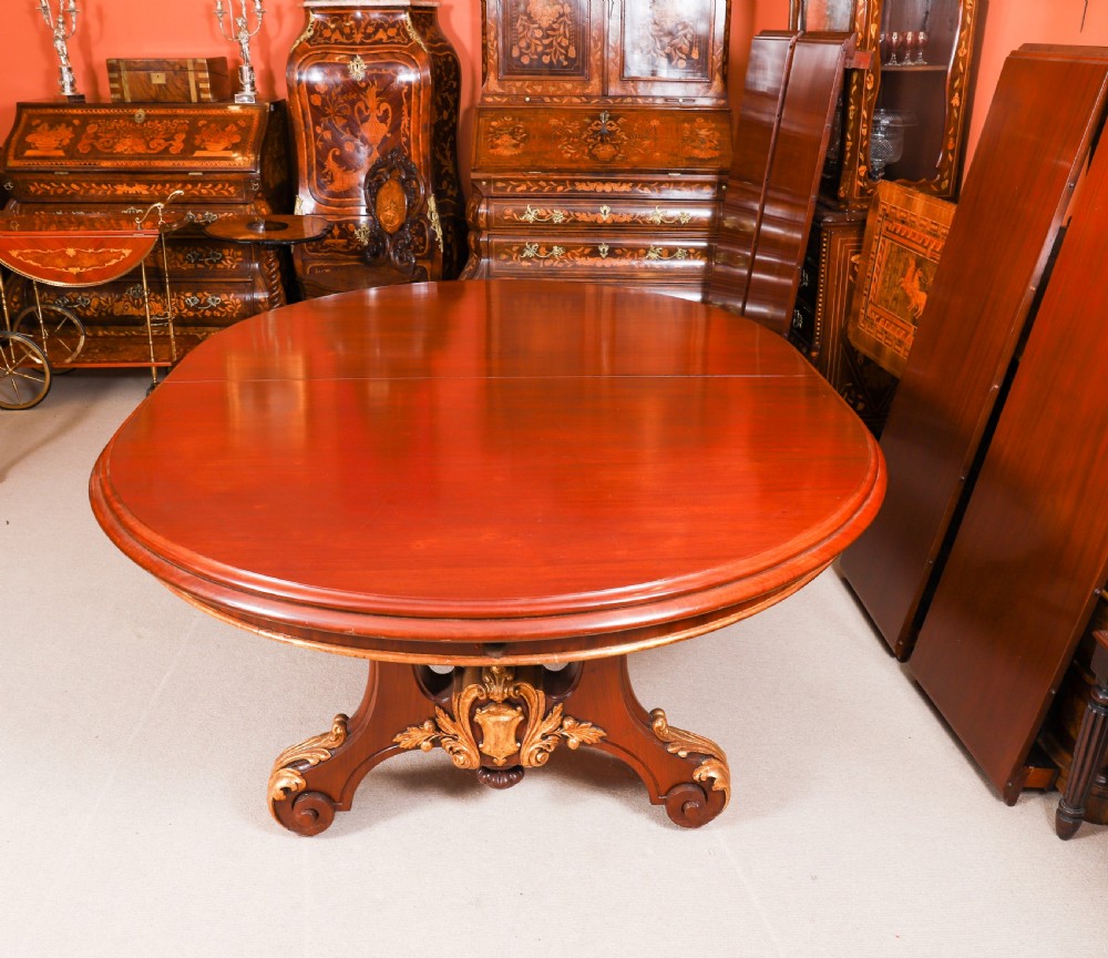 A large, polished mahogany extending dining table supported by two carved twin pedestals with parcel-gilt detailing. View XIV