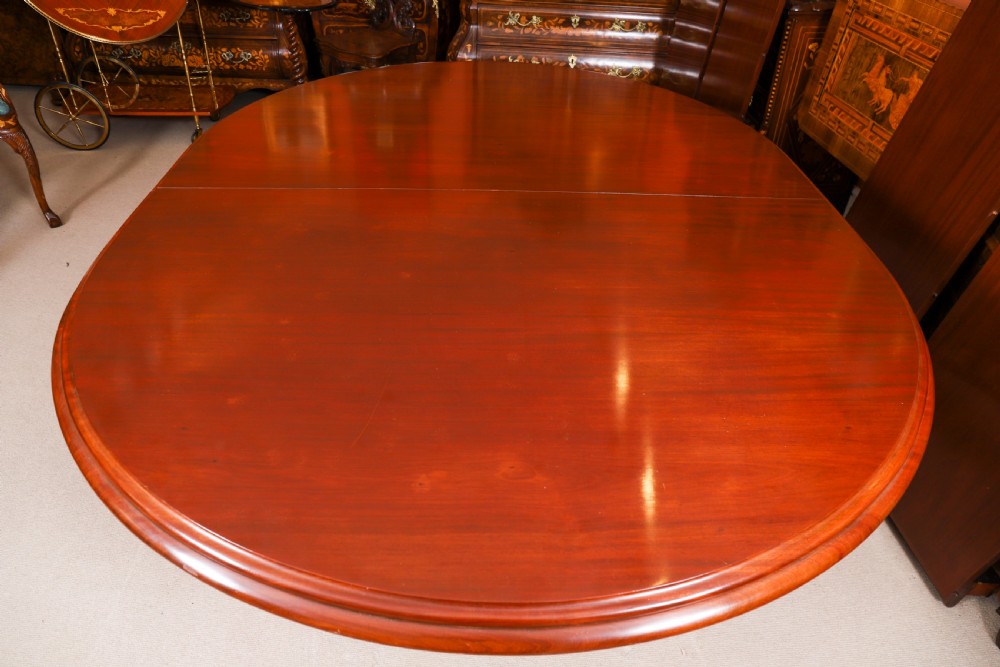 A large, polished mahogany extending dining table supported by two carved twin pedestals with parcel-gilt detailing. View XV