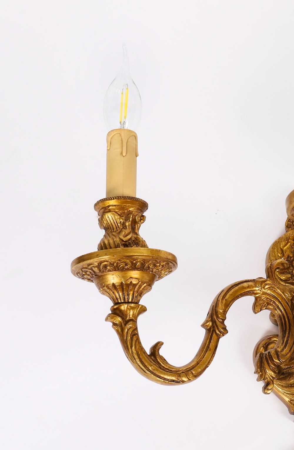 A set of four French Rococo style gilt bronze wall lights, each featuring three scrolling arms adorned with acanthus leaf motifs and candle drip sockets. View V