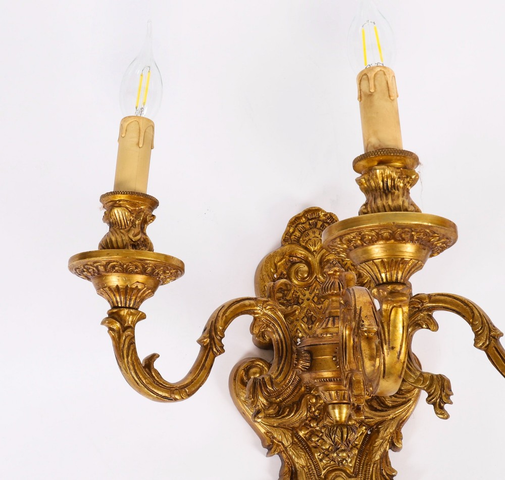 A set of four French Rococo style gilt bronze wall lights, each featuring three scrolling arms adorned with acanthus leaf motifs and candle drip sockets. View VII
