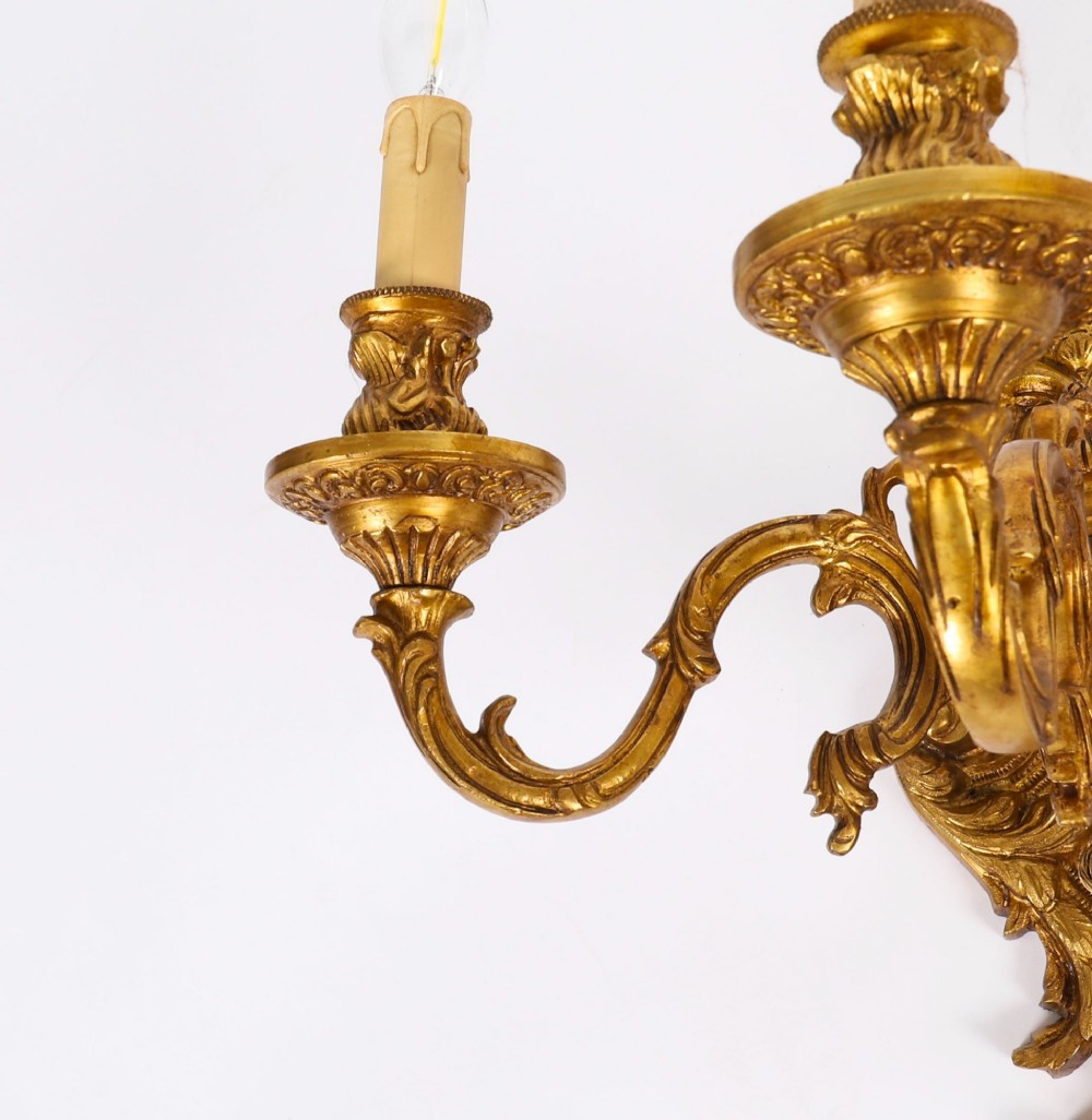 A set of four French Rococo style gilt bronze wall lights, each featuring three scrolling arms adorned with acanthus leaf motifs and candle drip sockets. View XIII
