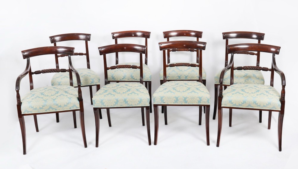 A set of eight Regency mahogany dining chairs, including two carvers, featuring curved top rails, rope-twist splats, and pale blue patterned upholstered seats.